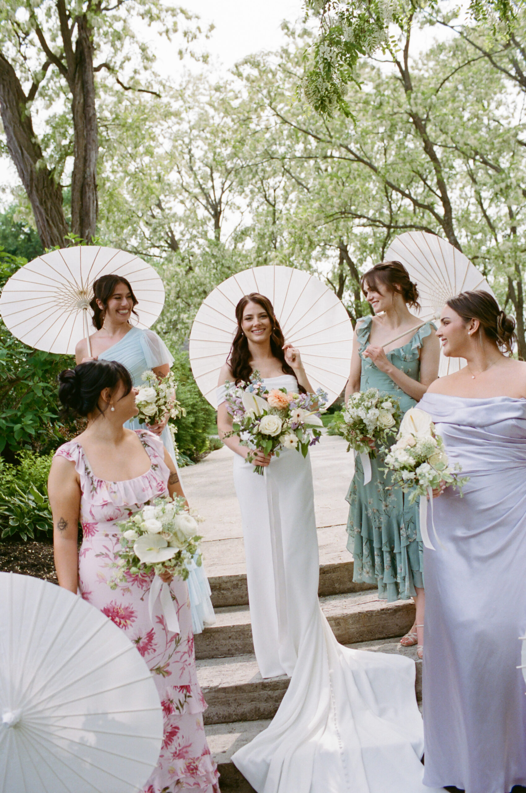 Bride and bridesmaids in mismatched dresses with parasol umbrellas at Stonefields Estate